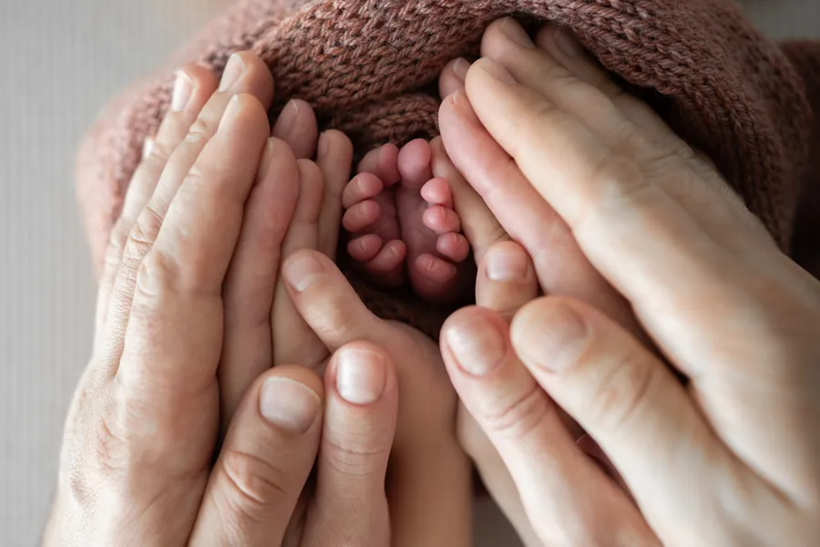 A close-up of hands holding a baby's feet