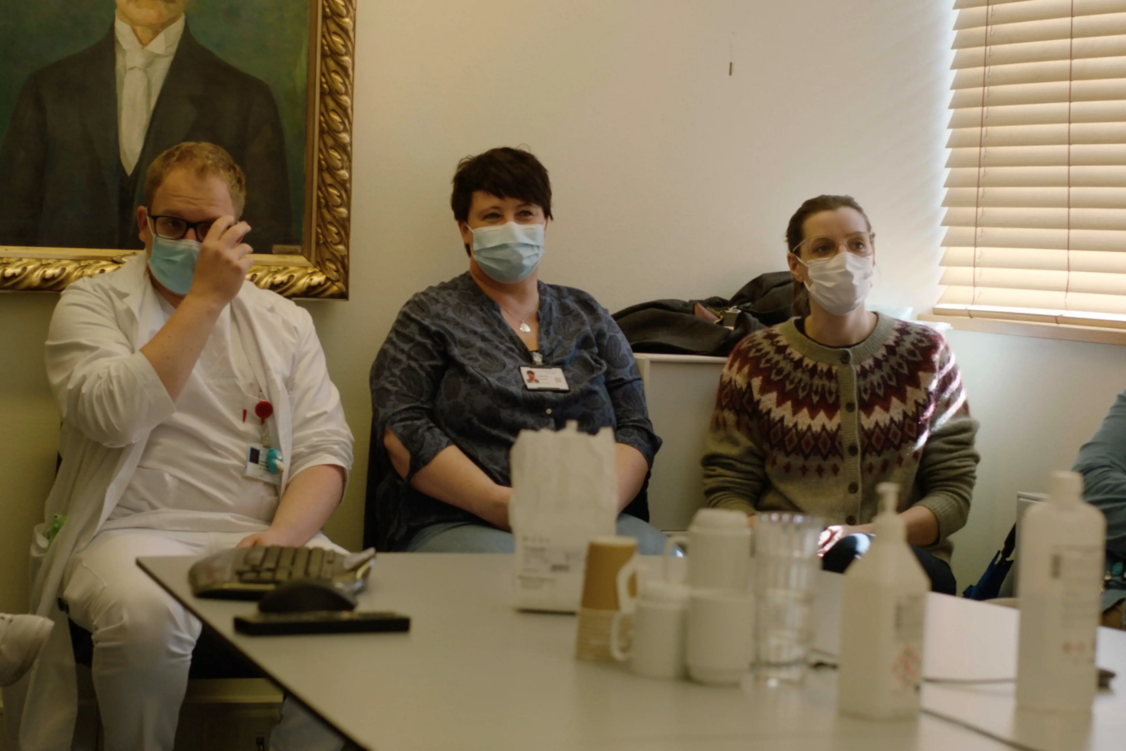 Helsepersonel sit i eit møte, munnbind på. Foto.