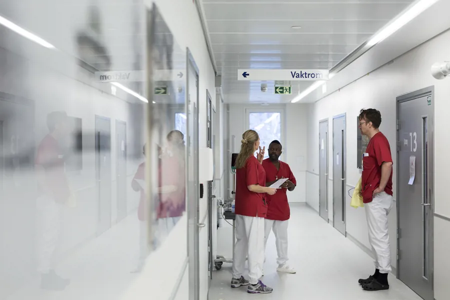Sykehuspersonale står og snakker i korridor. Foto.