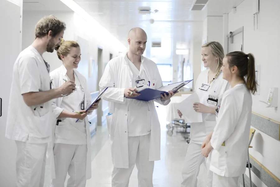 En gruppe mennesker i hvite labfrakker ser på et papir
