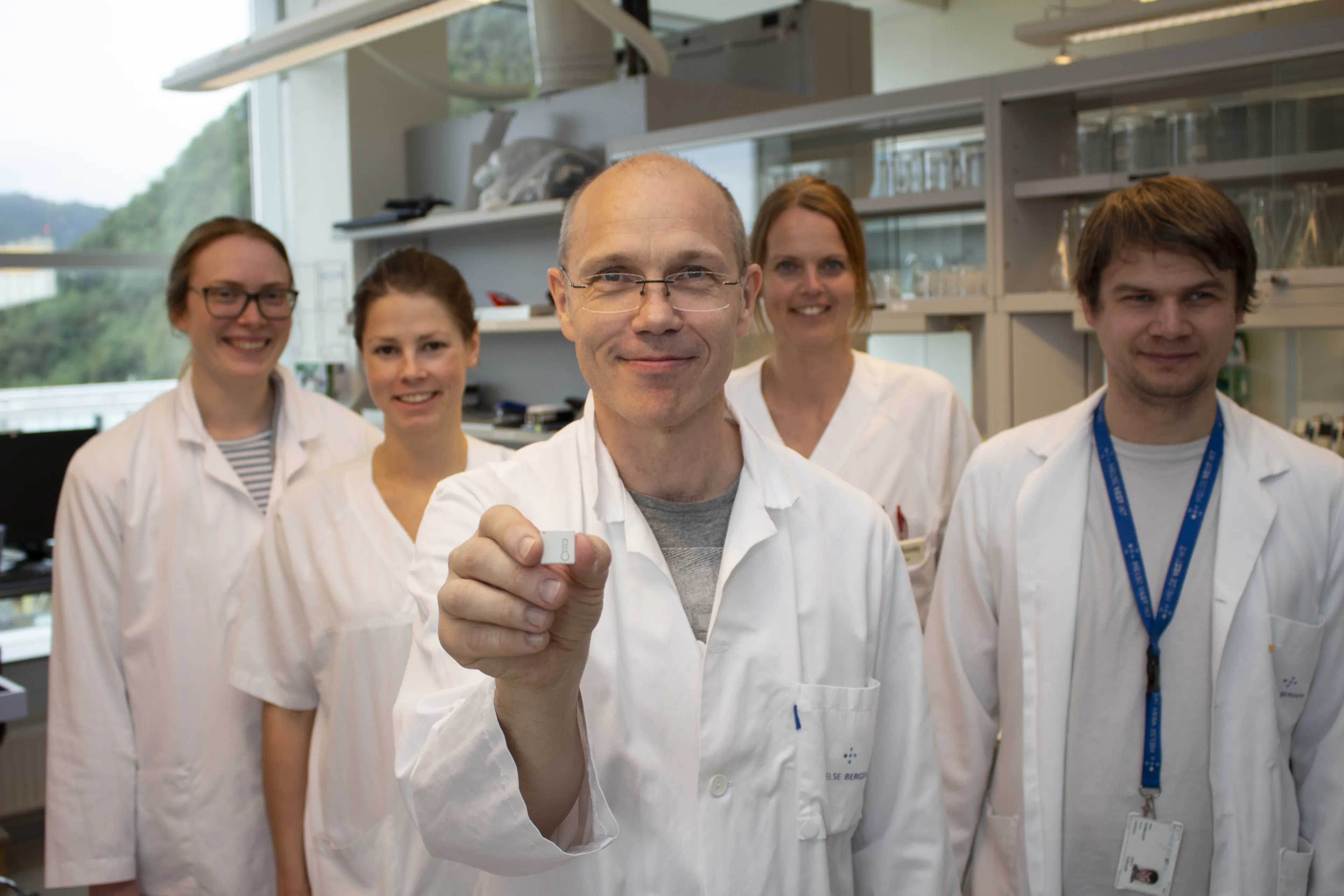 fem forskere i hvite klær viser frem en sensor